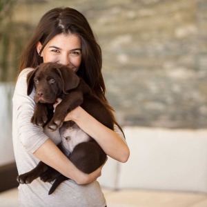 Young woman holding cute chocolate lab puppy