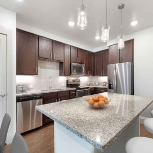 Kitchen only view of 1 bedroom home with modern appliances and tile blacksplash
